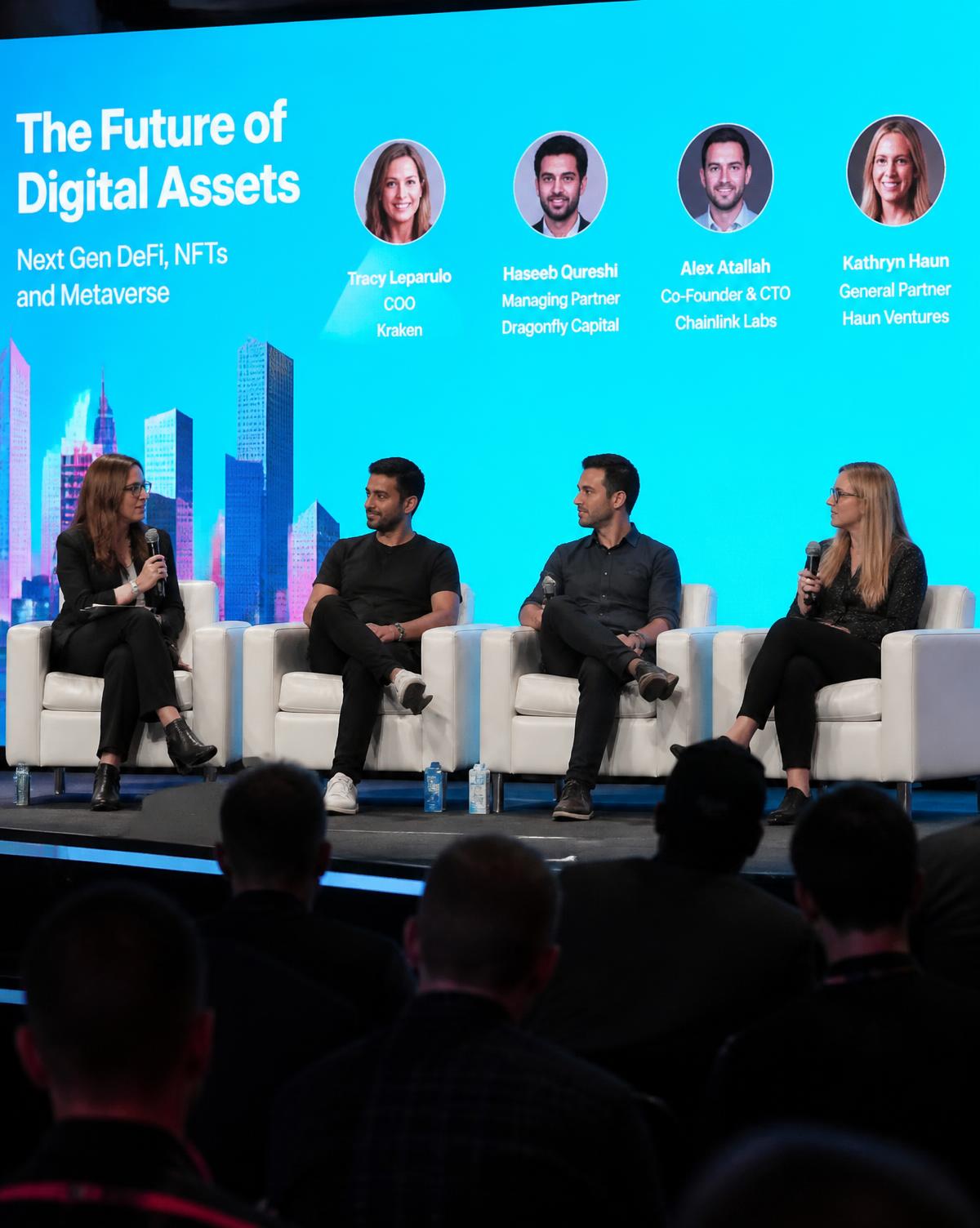 Speakers on a panel in front of a large crypto conference audience